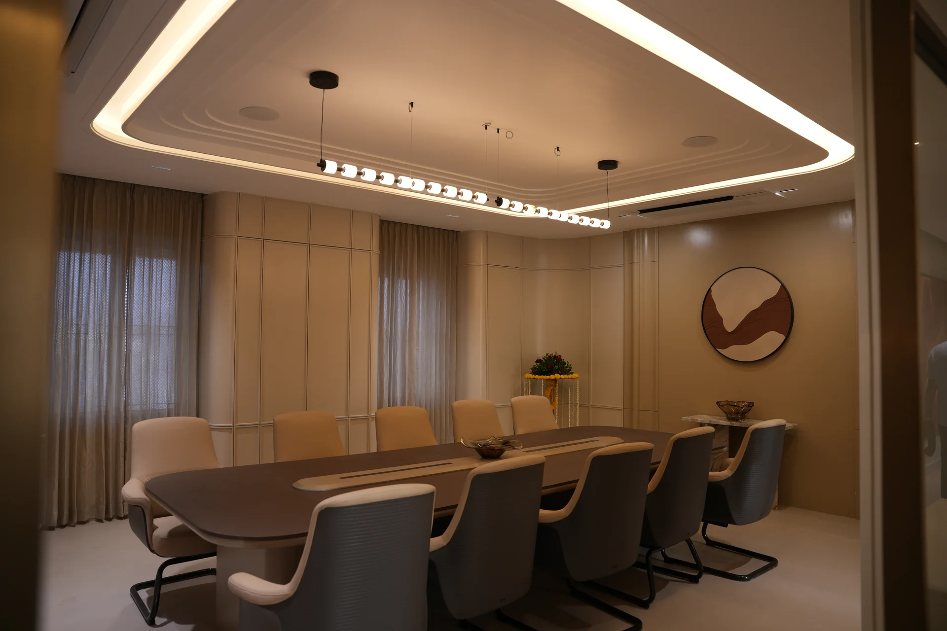 Office meeting room with a long conference table, upholstered chairs and warm ceiling lighting