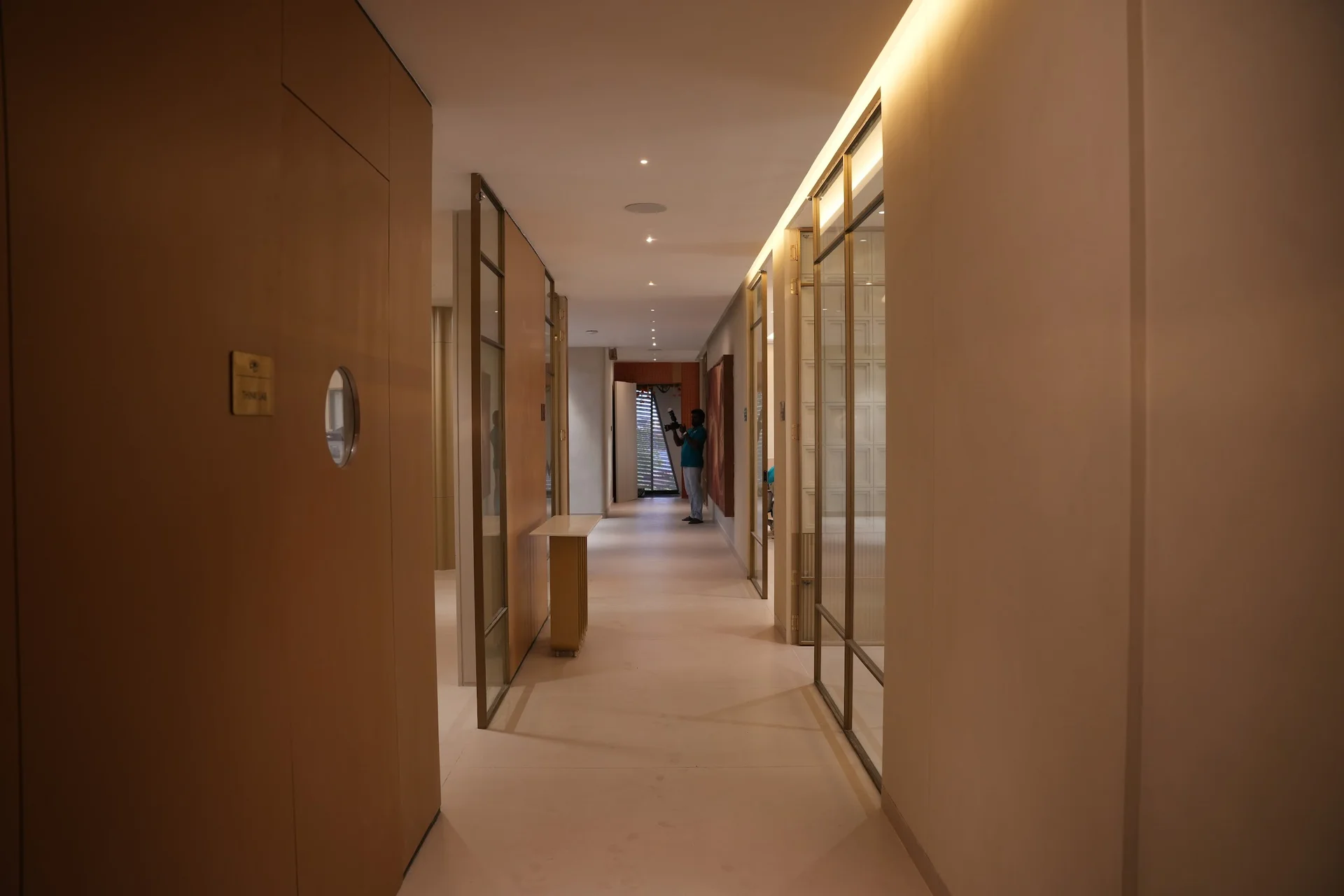 Warmly lit office corridor lined with glass-fronted rooms