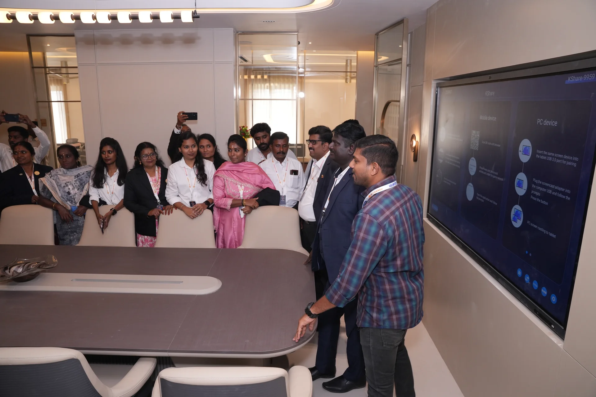 A group gathered around the conference table beside a large presentation screen