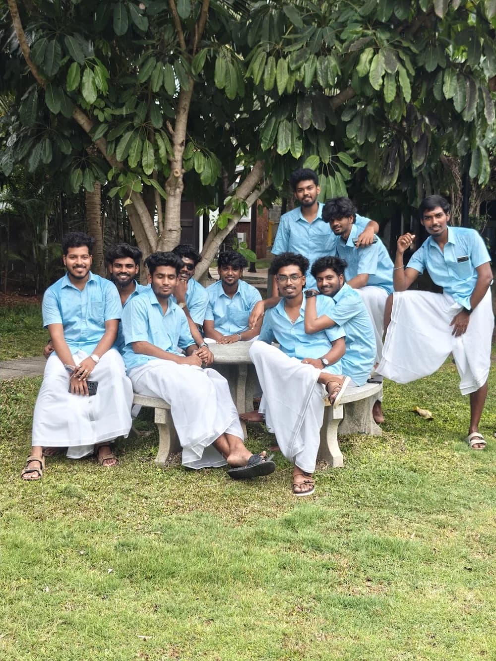 Team members gathered around a stone bench beneath a tree