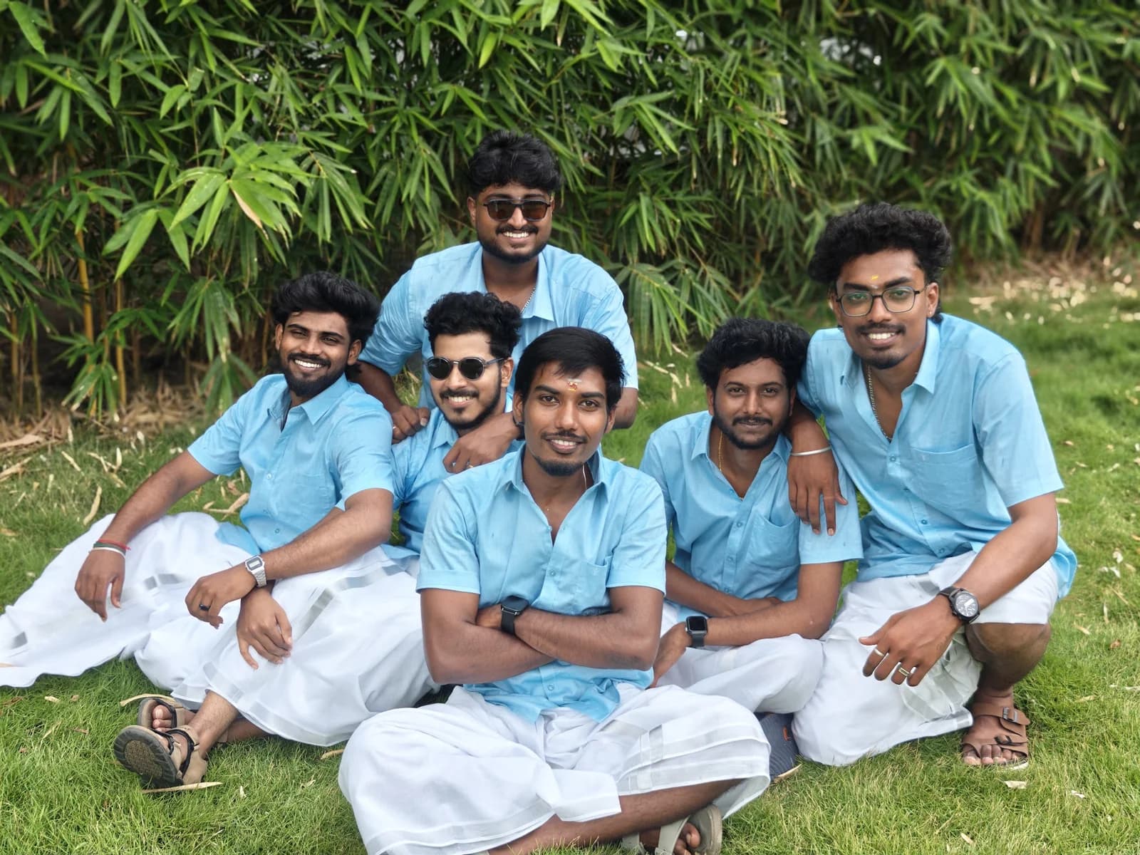 Six team members in blue shirts sitting together on the lawn