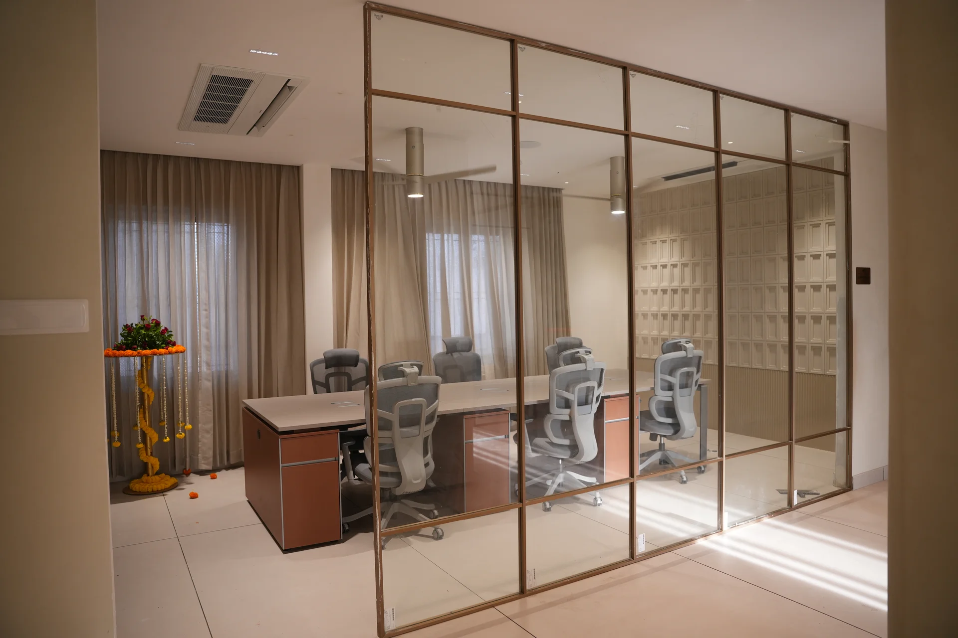 Shared desks and ergonomic chairs behind a glass office partition